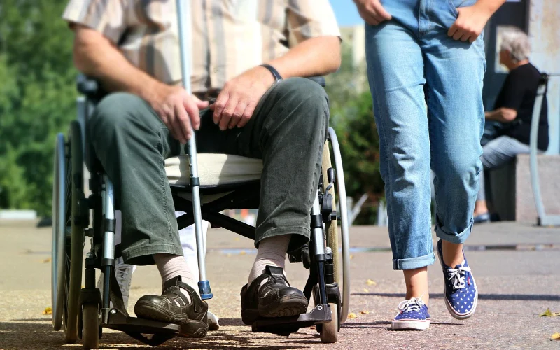 Male wheelchair user with a person walking alongside 